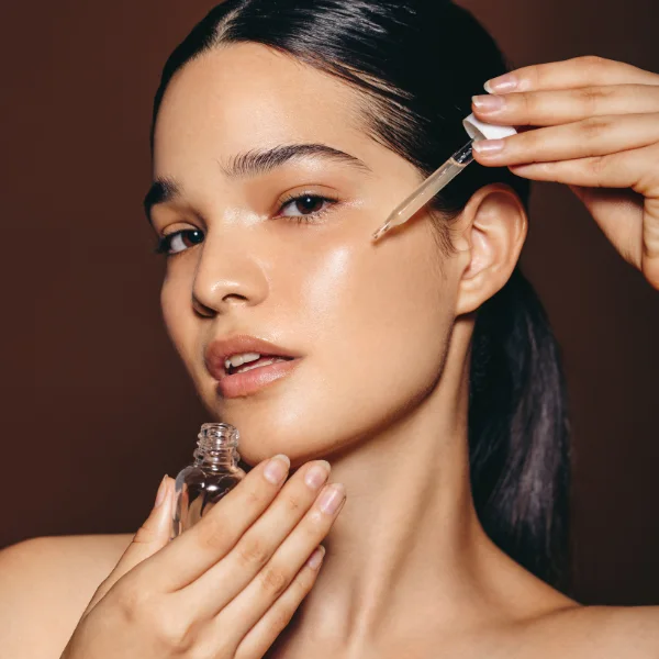 Skincare model holding a serum dropper beside her face